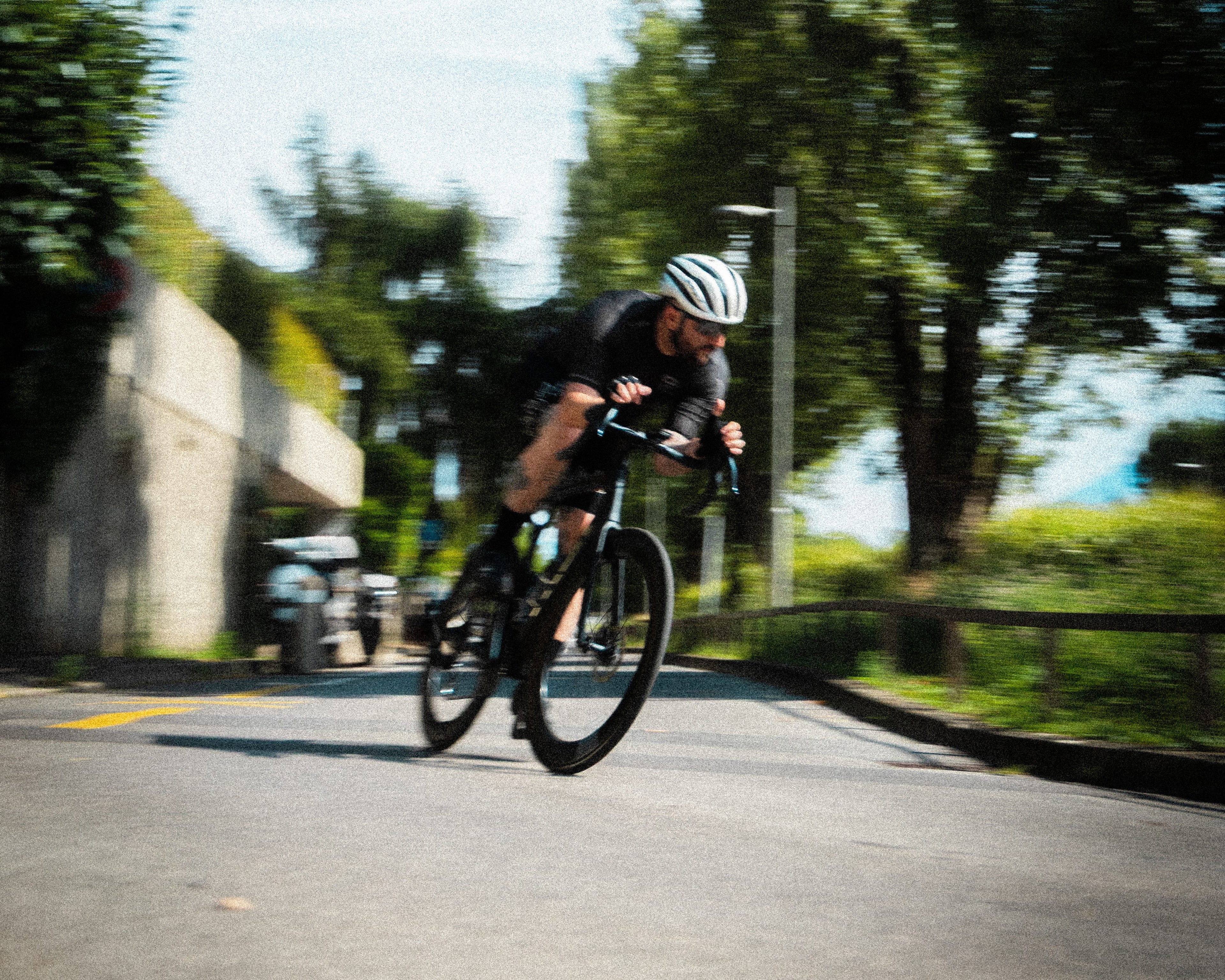 Person cycling on a road with trees and a clear sky in the background
